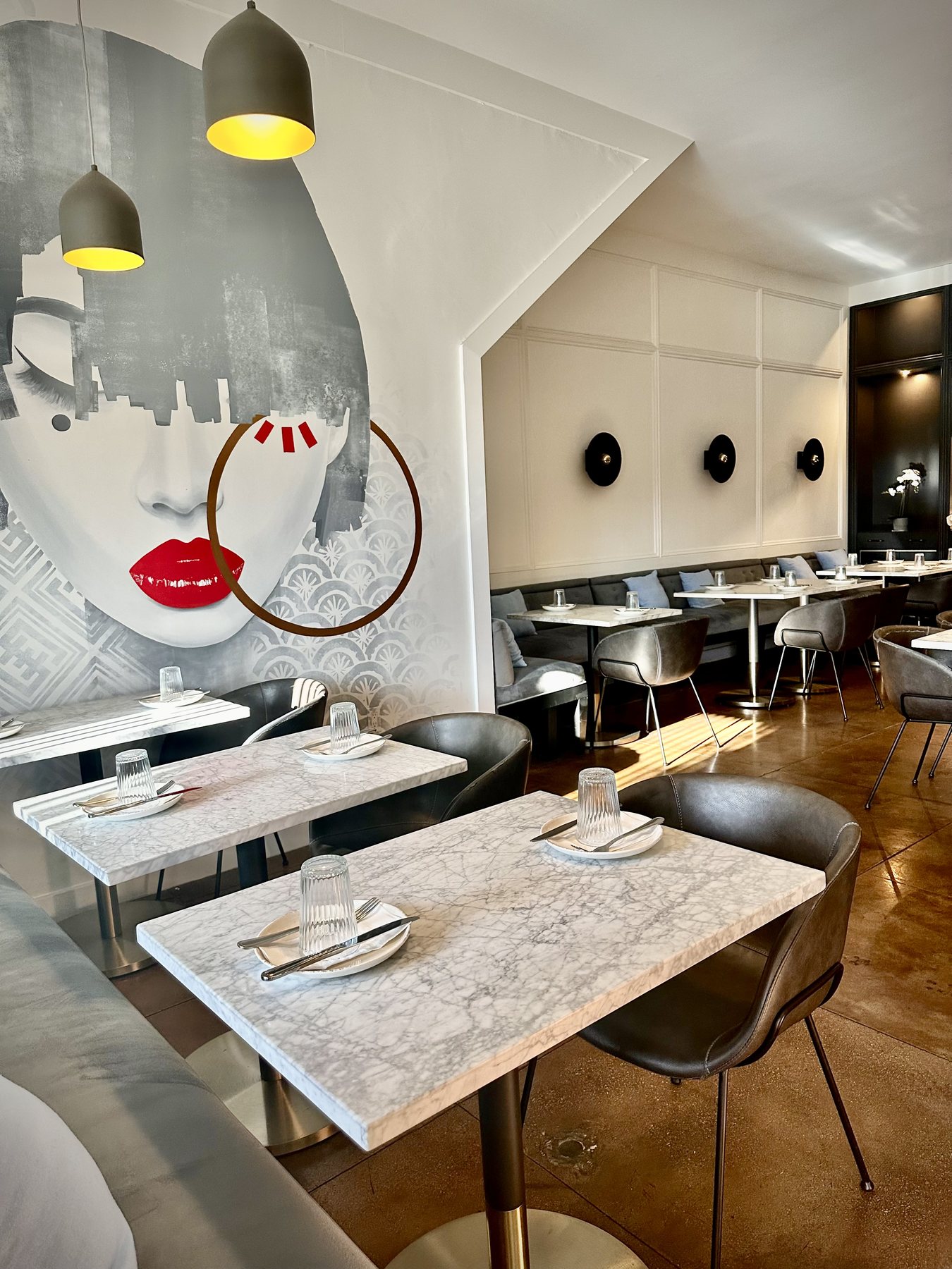 Dining room at Spelling Thai Bistro, with the mural, marble tables, and black chairs